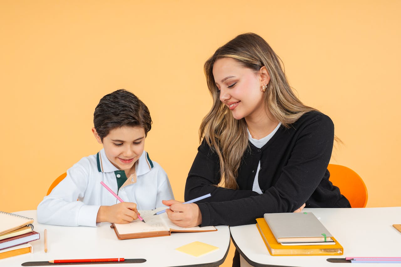 team-03 Young teacher helps a schoolboy with writing at a desk, fostering learning.