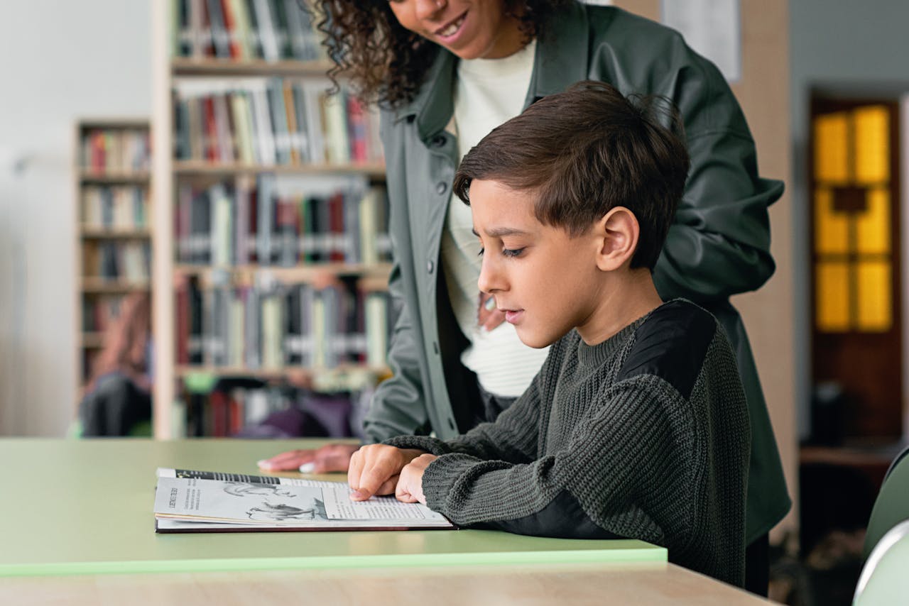 why-choose-us A young boy engages with a book in a library under guidance, fostering a love for learning.